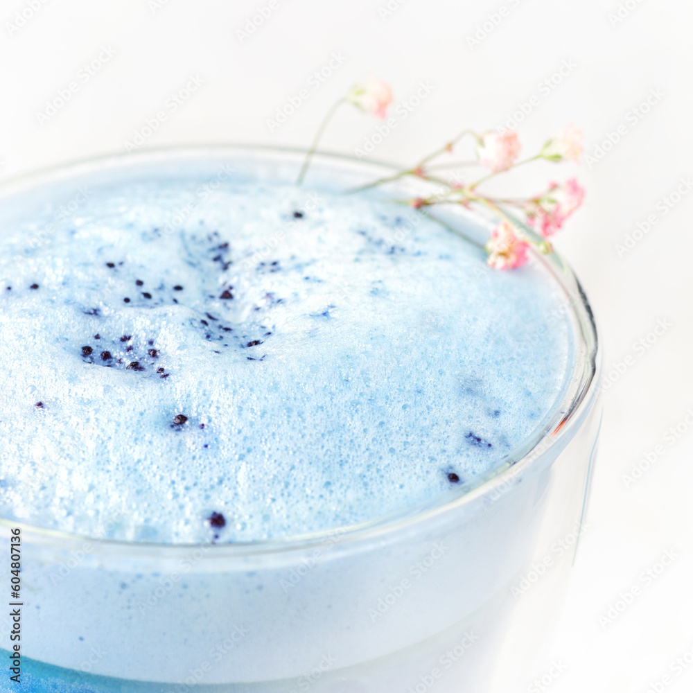 Blue matcha latte in a glass on a light white table. Blue matcha latte in a glass on a light white table.