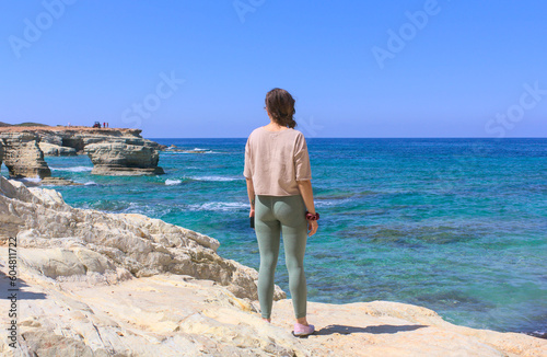 A woman enjoying the beautiful view of the bay and ATV quads in the distance on a sunny day. Paphos, Cyprus near the Edro III shipwreck. © Tula L
