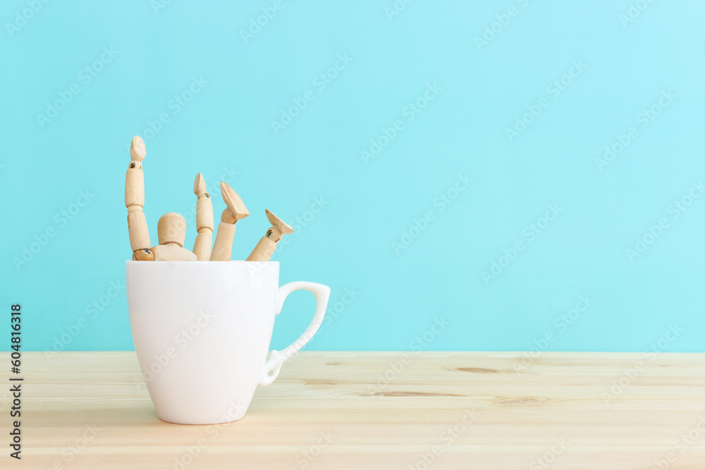 Funny picture of a wooden figure jumping into a cup of coffee Funny picture of a wooden figure jumping into a cup of coffee
