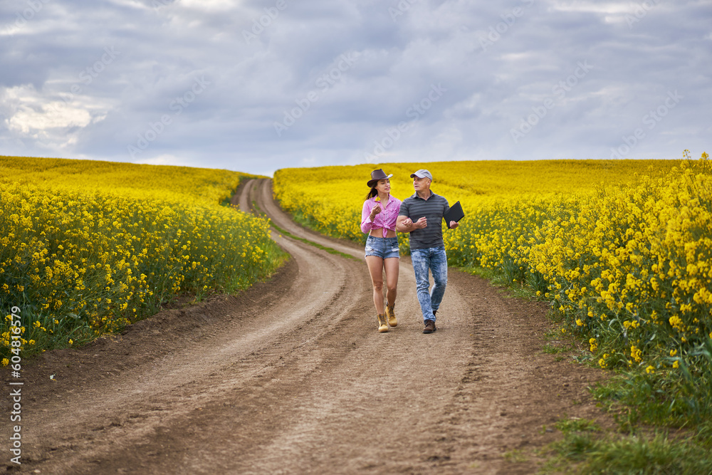 Obraz premium Farmers couple examining canola fields