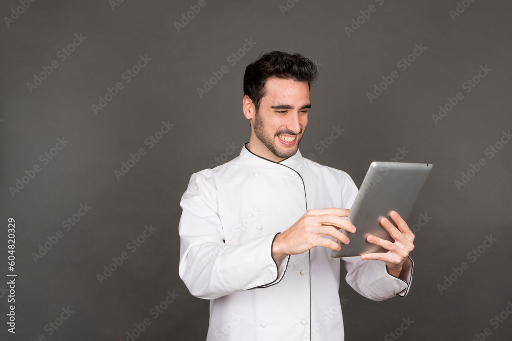 Smiling young male chef using tablet in studio Smiling young male chef using tablet in studio