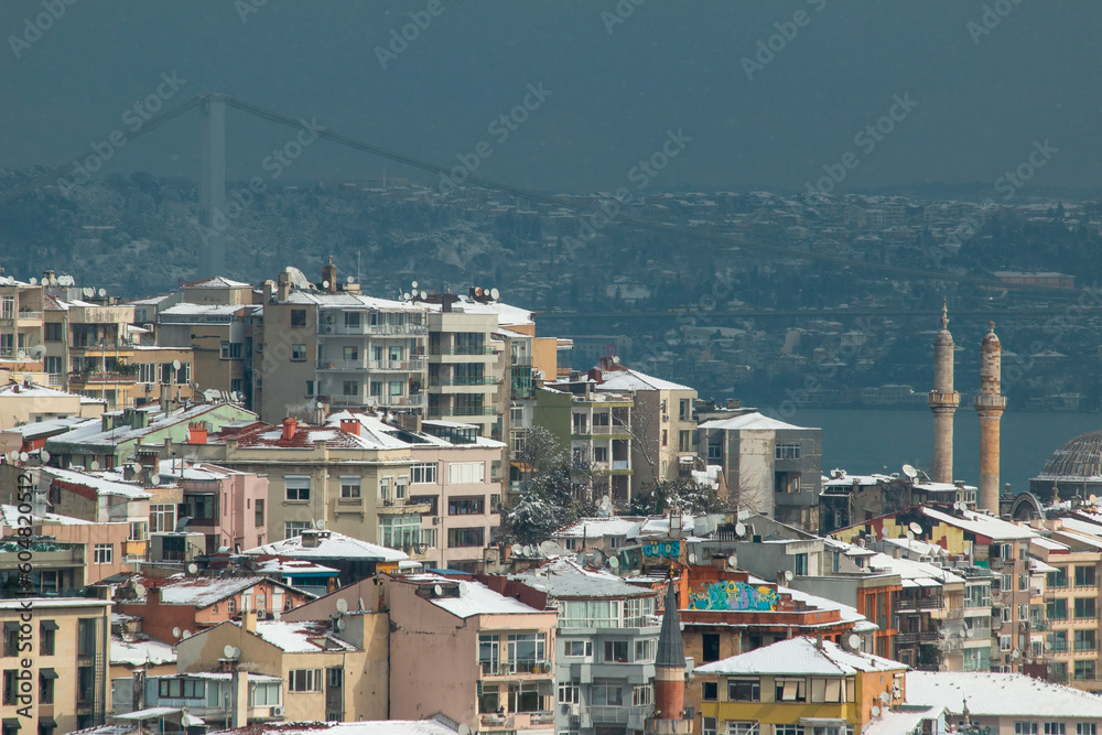 Istanbul city view in winter with snow covered houses roofs.