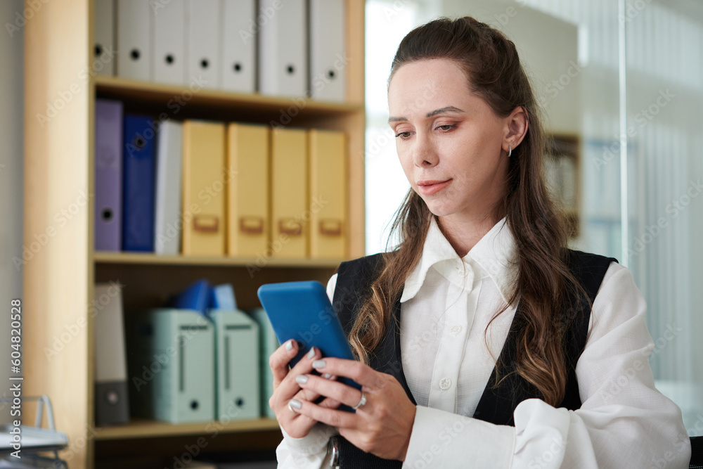 Businesswoman reading text message from client or coworker Businesswoman reading text message from client or coworker