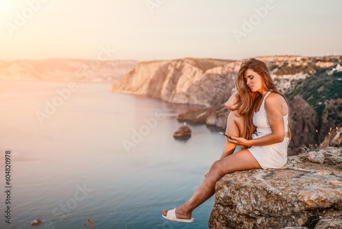 Woman travel sea. Happy tourist in hat enjoy taking picture outdoors for memories. Woman traveler posing on the beach at sea surrounded by volcanic mountains, sharing travel adventure journey © panophotograph