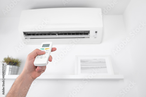 Obraz na płótnie Man holding a modern AC unit remote. w salonie