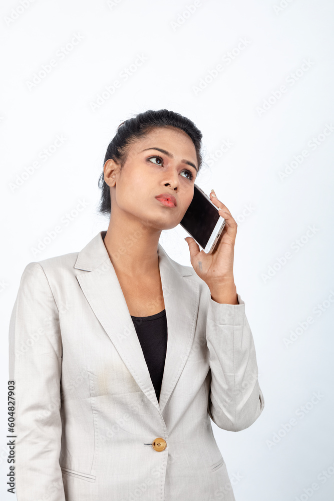 Corporate office lady with black hair having playful moment with pen, smart phone in formal wear wearing white blazer against white background. Corporate office lady with black hair having playful moment with pen, smart phone in formal wear wearing white blazer against white background.