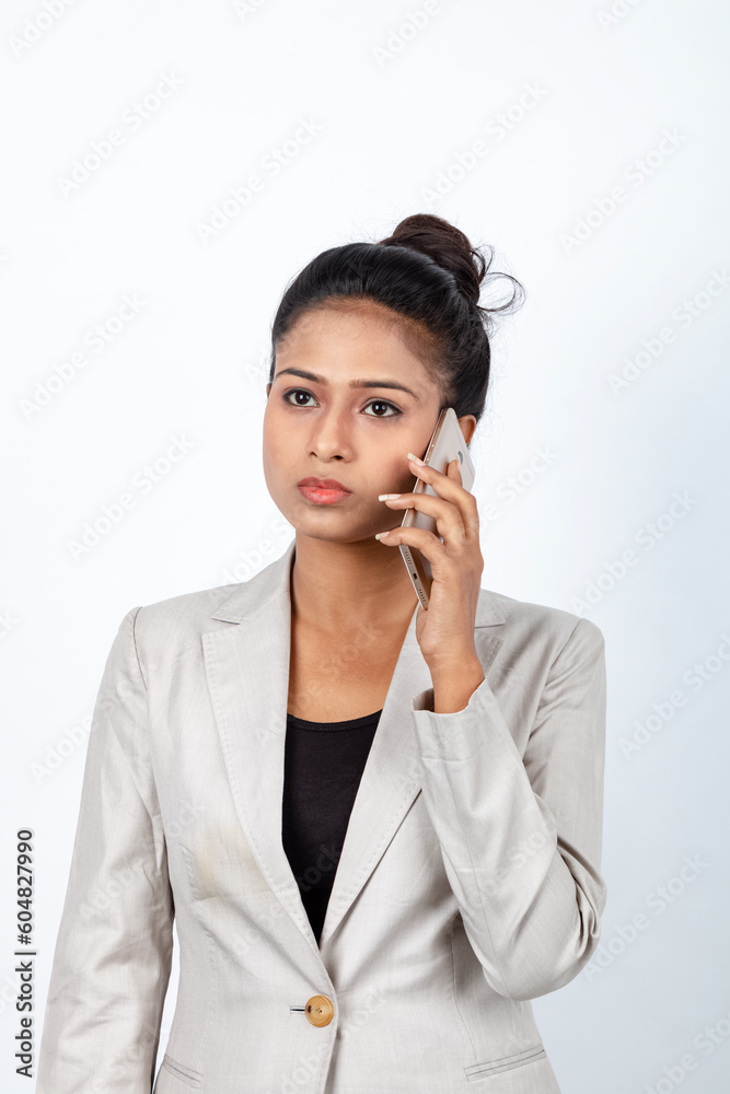 Corporate office lady with black hair having playful moment with pen, smart phone in formal wear wearing white blazer against white background. Corporate office lady with black hair having playful moment with pen, smart phone in formal wear wearing white blazer against white background.