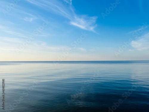 Blue sea horizon with some light clouds, seascape background © Oksana