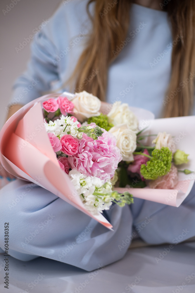 Woman with a delicate summer bouquet of flowers. The florist creates a red beautiful bouquet of mixed flowers. Flower shop. Fresh bouquet. Master classes and floristry courses. Flower delivery.