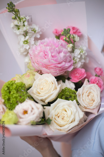 Woman with a delicate summer bouquet of flowers. The florist creates a red beautiful bouquet of mixed flowers. Flower shop. Fresh bouquet. Master classes and floristry courses. Flower delivery.