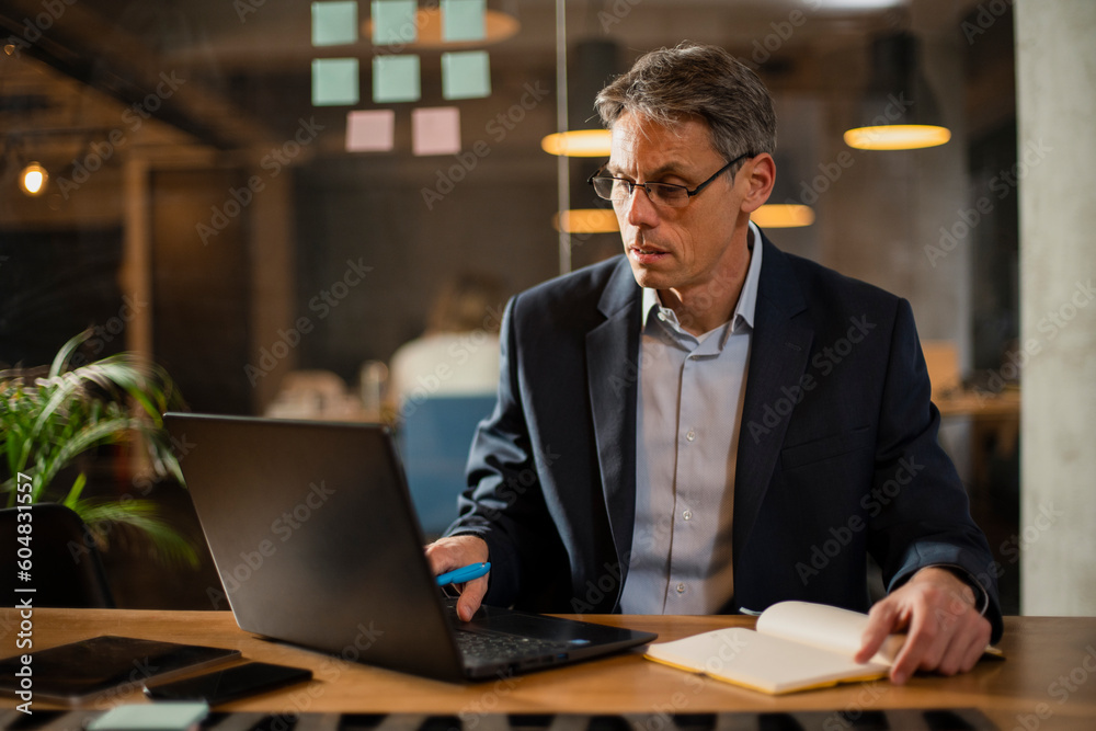 Businessman working with laptop at office. Businessman sitting at office desk working on laptop computer..