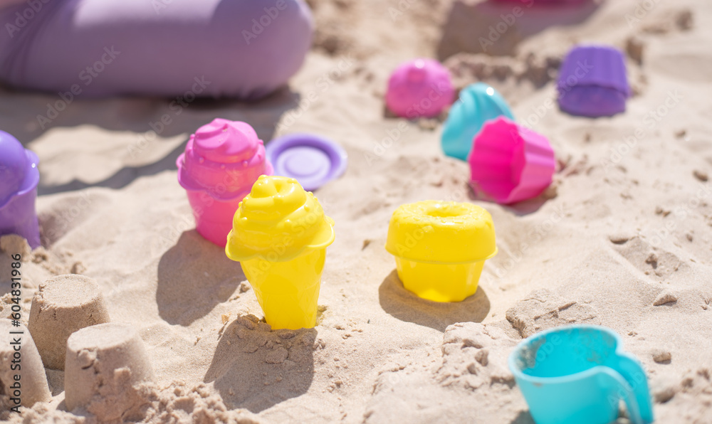 child play in stand with pink and yellow molds of ice cream for sand. Summer time joy and play in sand outdoor. Great vacation with children. child play in stand with pink and yellow molds of ice cream for sand. Summer time joy and play in sand outdoor. Great vacation with children.