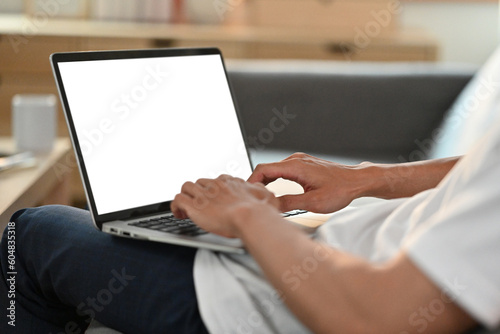 Man hands using laptop computer, typing on keyboard, searching information, working remote from home