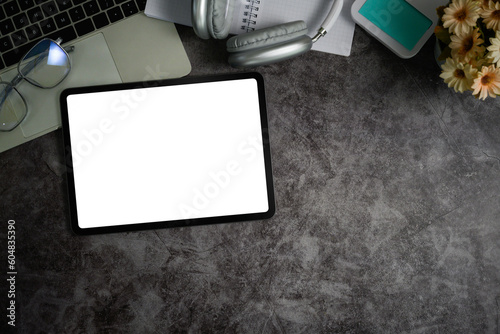 Flat lay, top view of digital tablet, headphone, laptop and supplies on gray stone background with space for text