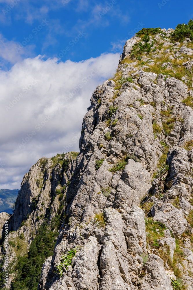 Vertical photo of a part of a mountain range against a blue sky background.