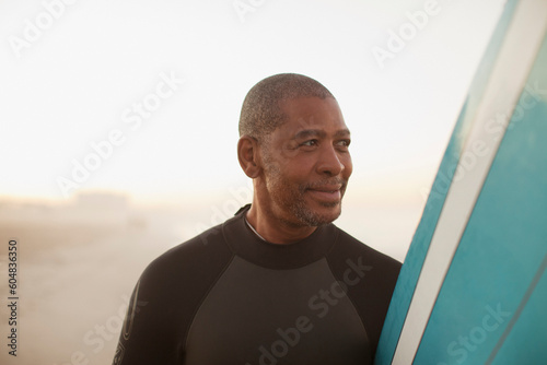 Older surfer carrying board on beach © KOTO