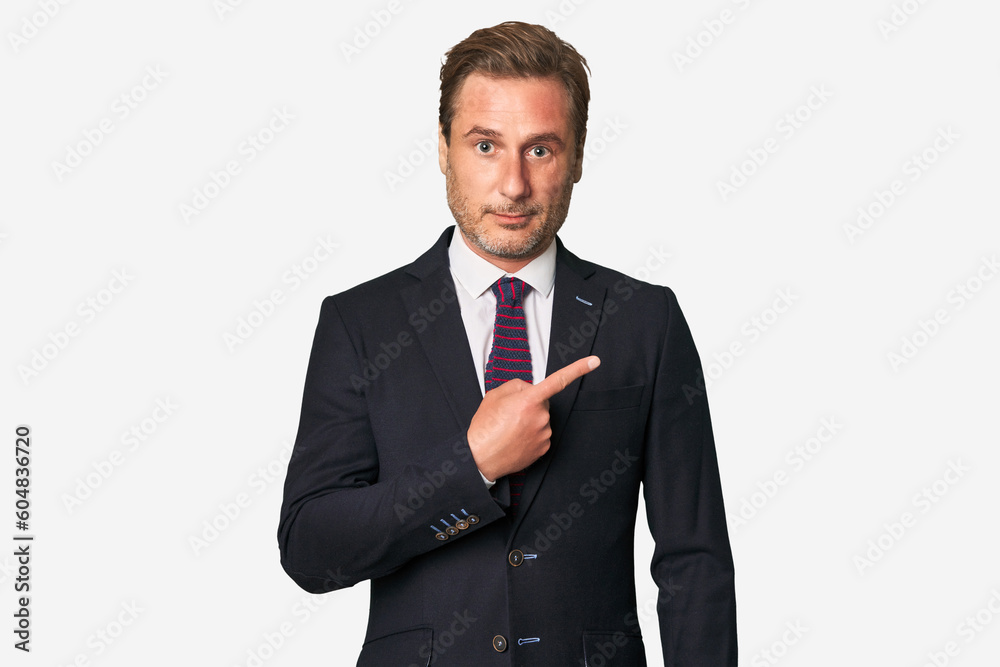 A middle-aged businessman isolated smiling and pointing aside, showing something at blank space. A middle-aged businessman isolated smiling and pointing aside, showing something at blank space.