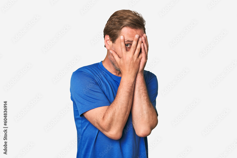 A middle-aged man isolated blink through fingers frightened and nervous. A middle-aged man isolated blink through fingers frightened and nervous.