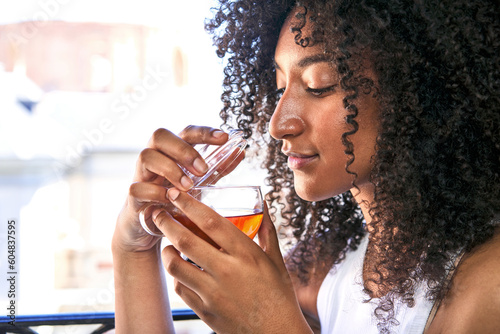 Photography African-American woman peacefully indulges in tea on her balcony, embracing the concept of relaxation