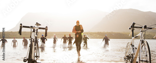 Obraz na płótnie Triathletes running to bicycles on beach