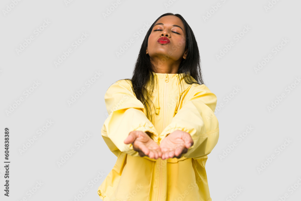 Young Indian woman cut out isolated on white background folding lips and holding palms to send air kiss. Young Indian woman cut out isolated on white background folding lips and holding palms to send air kiss.