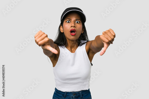 Young Indian woman cut out isolated on white background showing thumb down and expressing dislike.