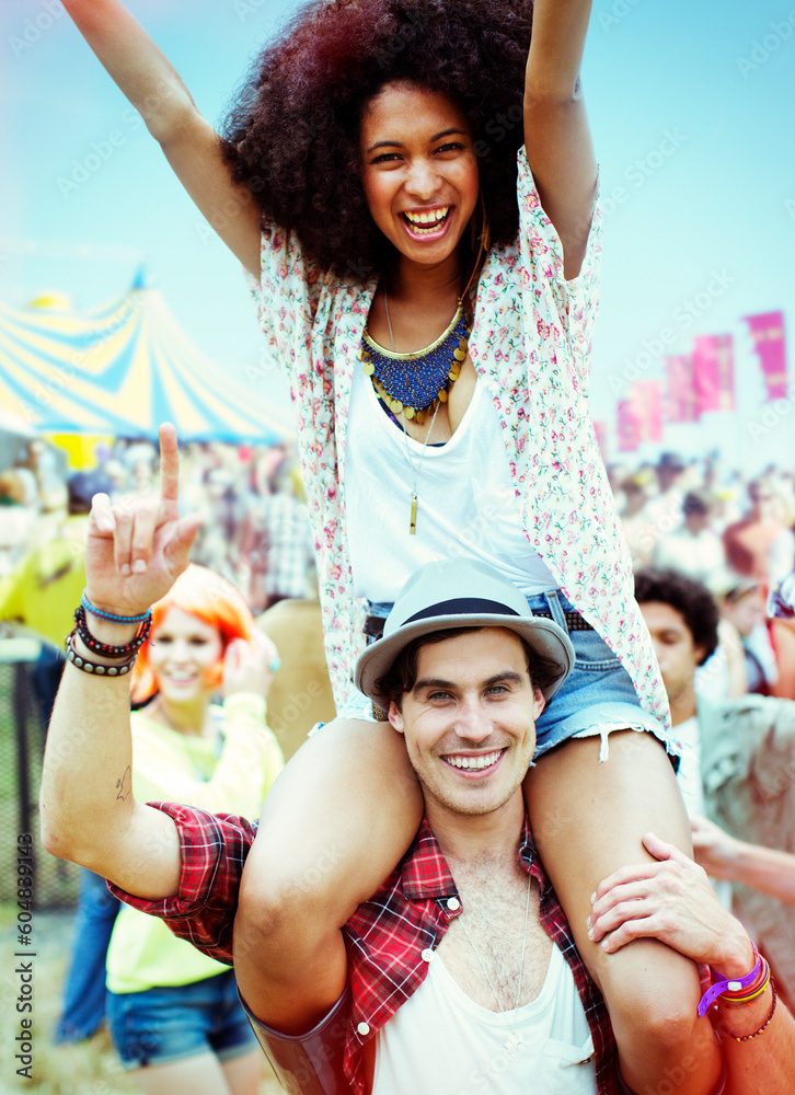 Portrait man carrying enthusiastic woman on shoulders at music festival