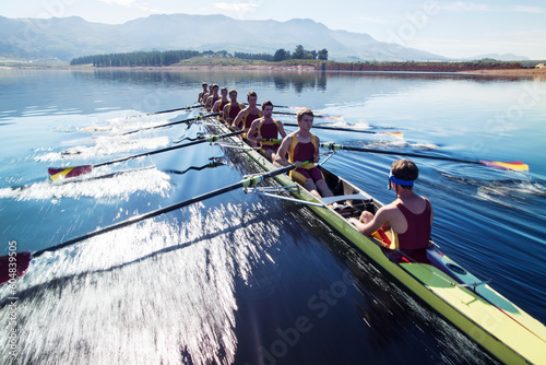 Rowing team rowing scull on lake photo