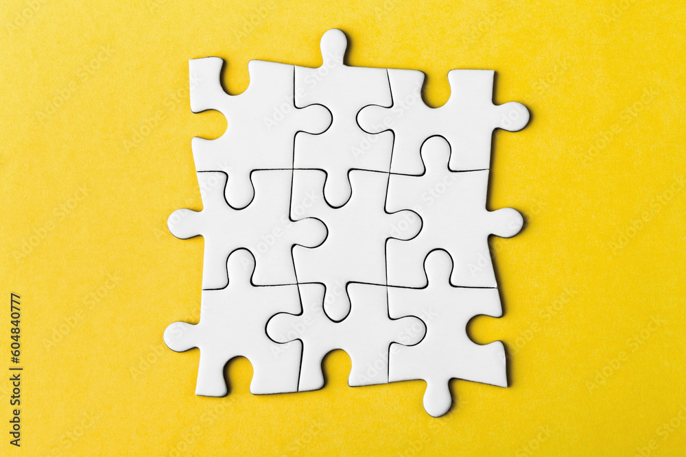 Fototapeta premium Pieces of a puzzle united among themselves on a yellow background.