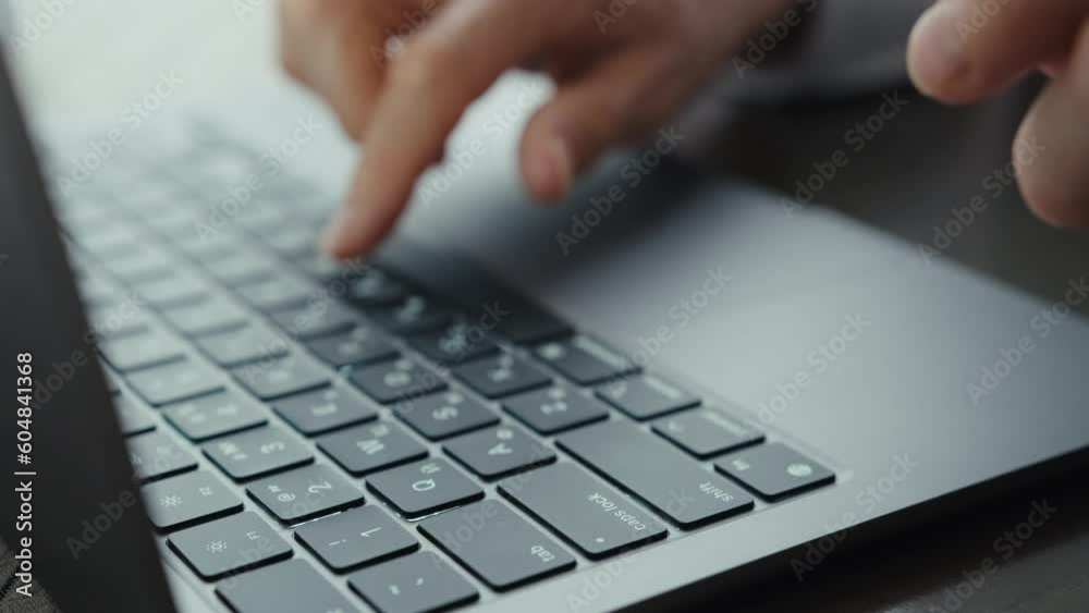 An elderly woman in a white shirt sits at a wooden table and works at a laptop. A woman in black glasses is typing on a keyboard. An elderly woman in a white shirt sits at a wooden table and works at a laptop. A woman in black glasses is typing on a keyboard.