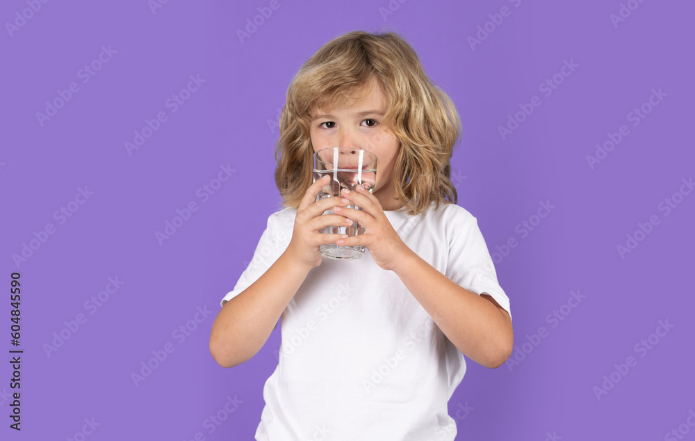 Little kid drinking a fresh glass of water, isolated on studio background. Thirsty child holding glass drinks still water. Portrait of kid boy drinking pure water from glass. Little kid drinking a fresh glass of water, isolated on studio background. Thirsty child holding glass drinks still water. Portrait of kid boy drinking pure water from glass.