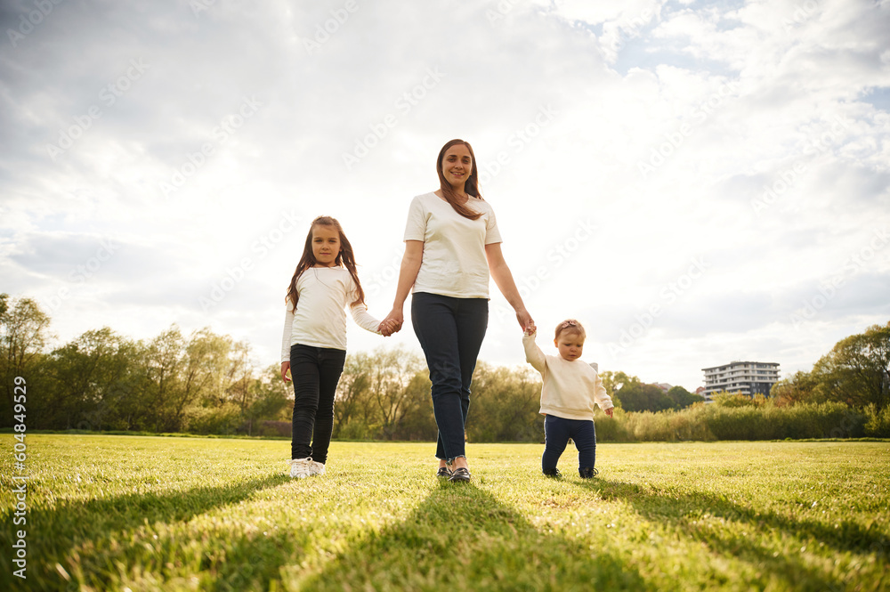 Woman with her two young daughters is on the summer field