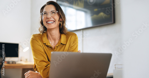 Confident businesswoman with eyeglasses laughing in her office