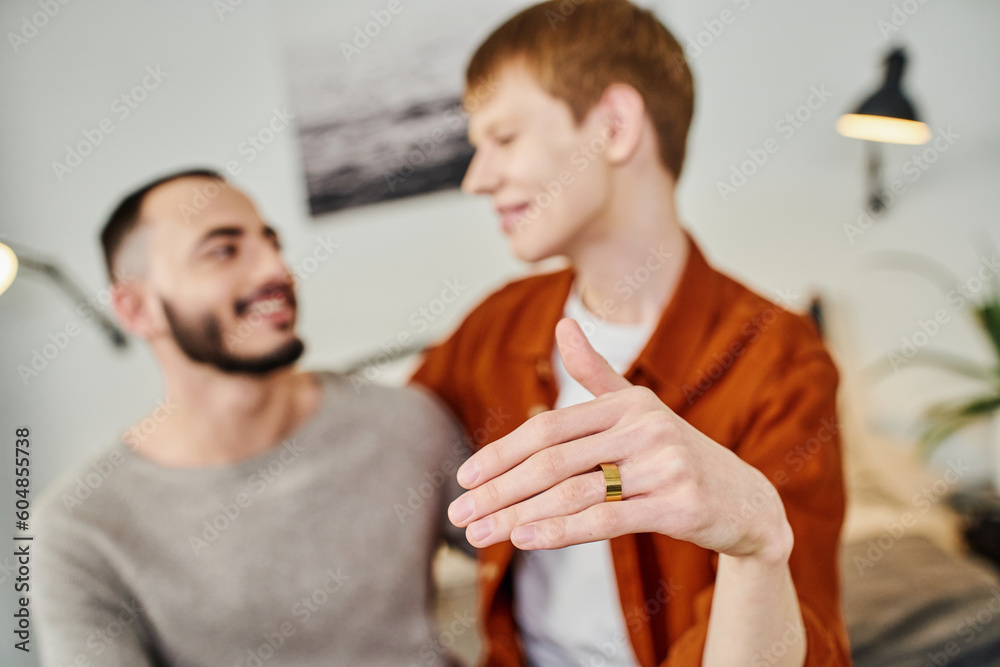 Fototapeta premium blurred gay man showing wedding ring near boyfriend at home.