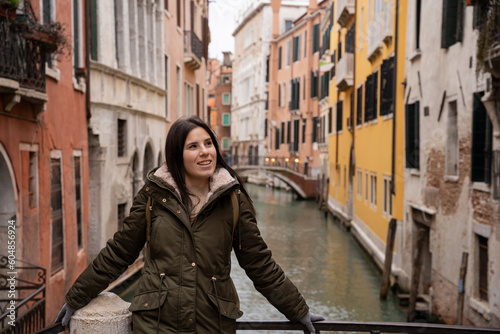 Young woman tourist on a Venice canal bridge amidst colorful facades