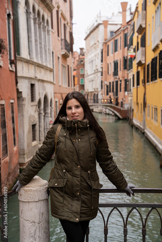 Young woman tourist on a Venice canal bridge amidst colorful facades