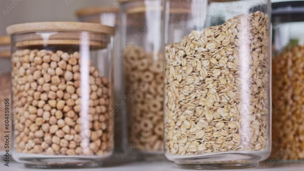 Glass jars filled with sunflower seeds, beans, lentils, and peas spin on the table. The bright kitchen is awash with sunlight, highlighting the healthy, bountiful food supplies and offerings. Glass jars filled with sunflower seeds, beans, lentils, and peas spin on the table. The bright kitchen is awash with sunlight, highlighting the healthy, bountiful food supplies and offerings.