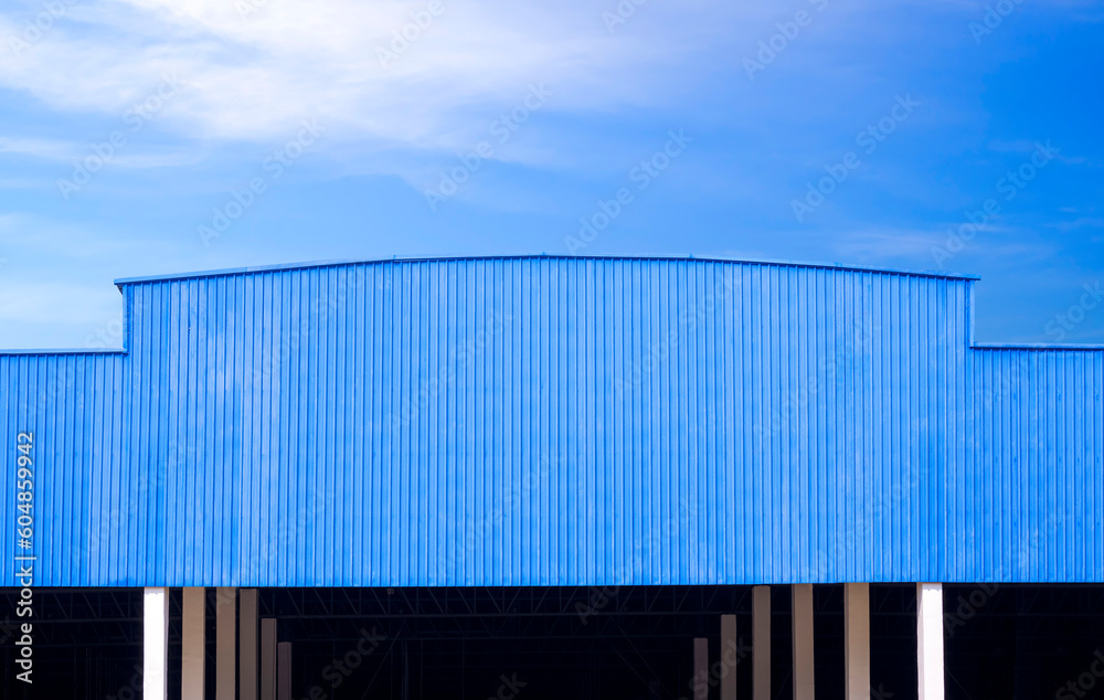 Blue Corrugated metal  Roof of large Industrial Warehouse Building against blue sky Background