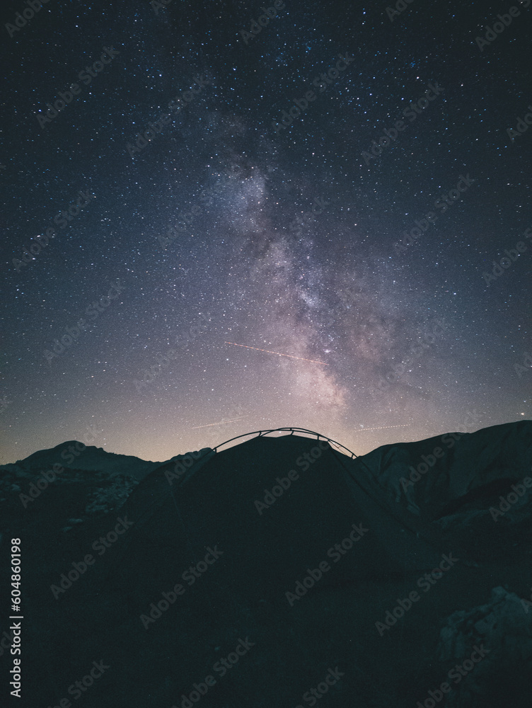 Tent high in the mountains under the night sky with the milky way.