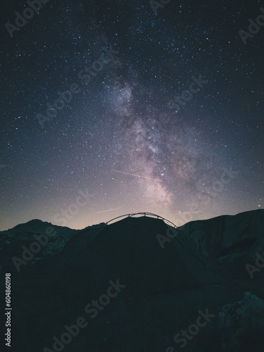 Tent high in the mountains under the night sky with the milky way.
