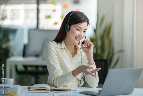 Portrait of happy smiling female customer support phone operator at workplace. Asian