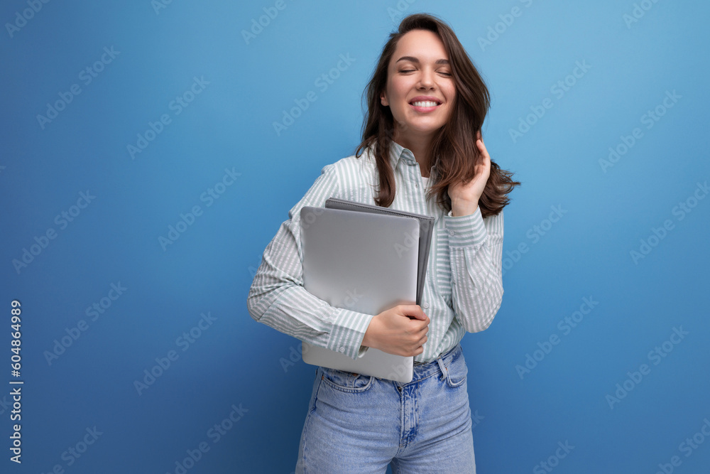 brunette young business woman in shirt with documents and laptop against background with copy pace brunette young business woman in shirt with documents and laptop against background with copy pace