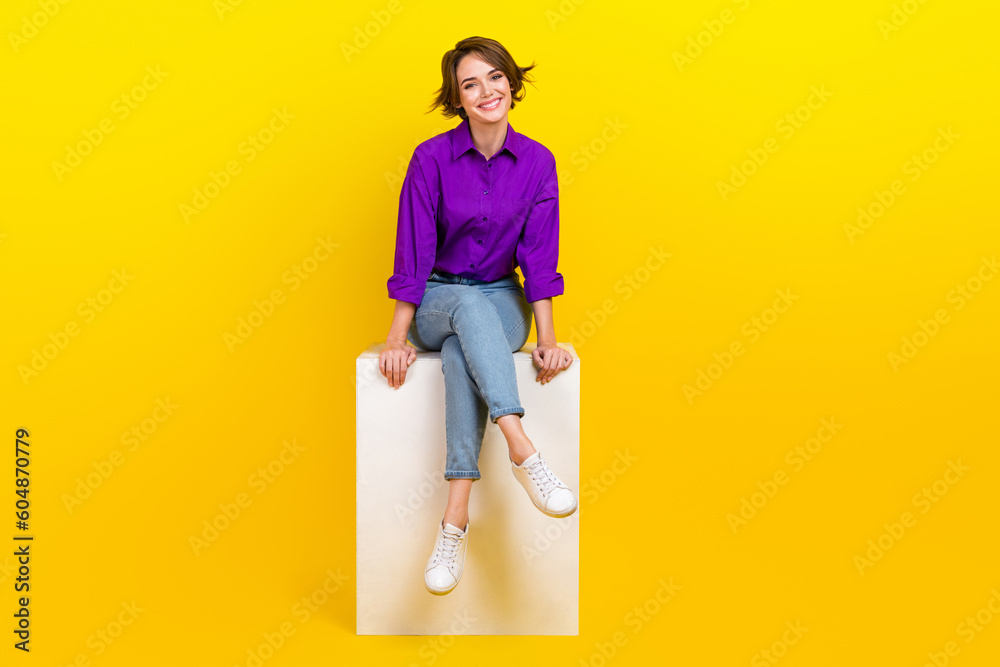Full body photo of attractive young woman sit white cube wear trendy violet smart casual clothes isolated on yellow color background Full body photo of attractive young woman sit white cube wear trendy violet smart casual clothes isolated on yellow color background
