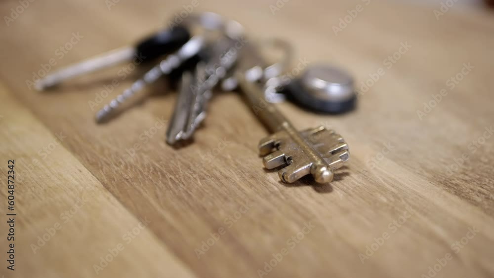 Close up, Bunch of Iron Keys to the Apartment on a Rotating Wooden Background. Texture. Selective focus. Top view. Blurred background. Concept of buying real estate, house, and car. Slow spin. Ring. Close up, Bunch of Iron Keys to the Apartment on a Rotating Wooden Background. Texture. Selective focus. Top view. Blurred background. Concept of buying real estate, house, and car. Slow spin. Ring.