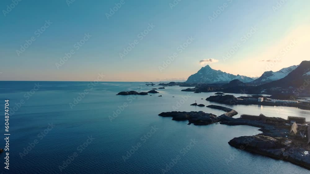 Aerial drone shot of the blue ocean in Lofoten, Norway with rocks in the foreground and mountains in the background. Aerial drone shot of the blue ocean in Lofoten, Norway with rocks in the foreground and mountains in the background.