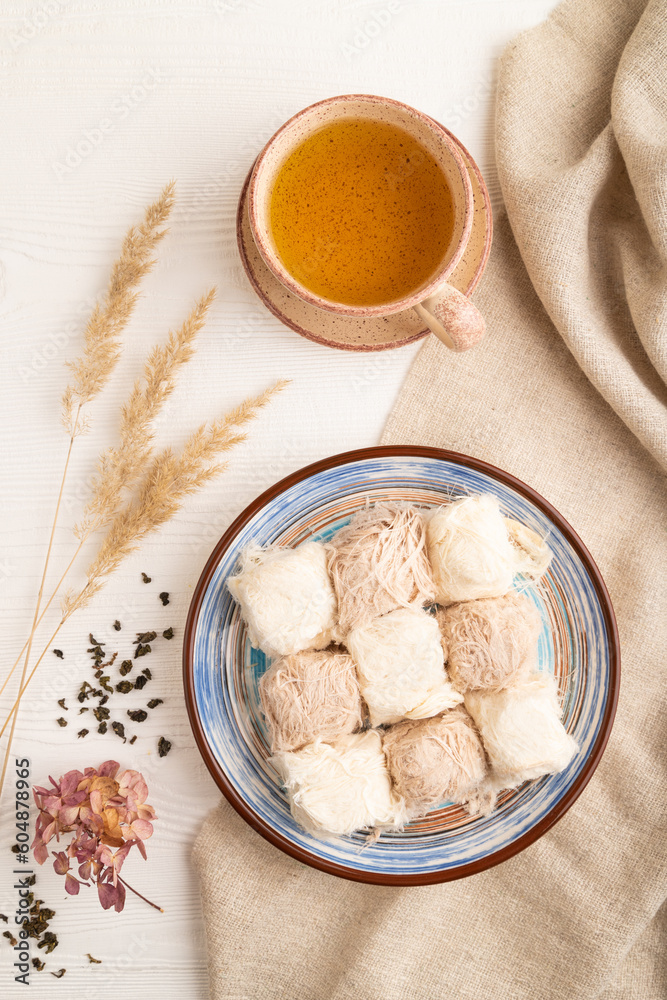traditional arabic sweets pishmanie and a cup of green tea on white wooden, top view. traditional arabic sweets pishmanie and a cup of green tea on white wooden, top view.