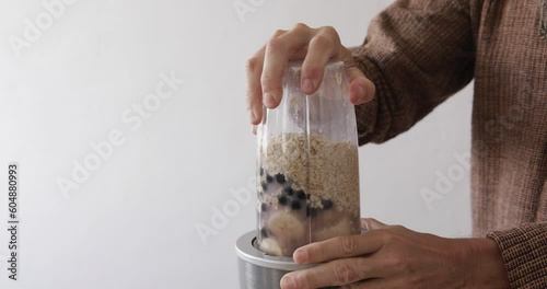Oatmeal milk smoothie with banana and chokeberry preparing, loading and starting food processor