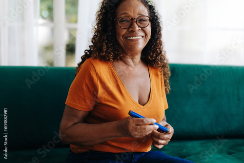 Mature woman using a smart insulin pen to control her blood sugar photo