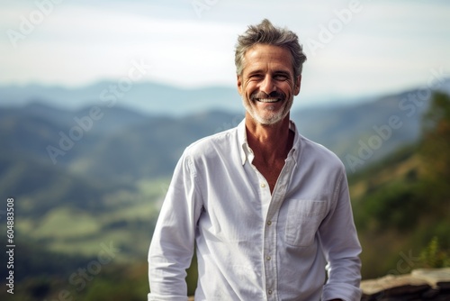 Lifestyle portrait photography of a grinning mature man wearing an elegant long-sleeve shirt against a scenic mountain overlook background. With generative AI technology