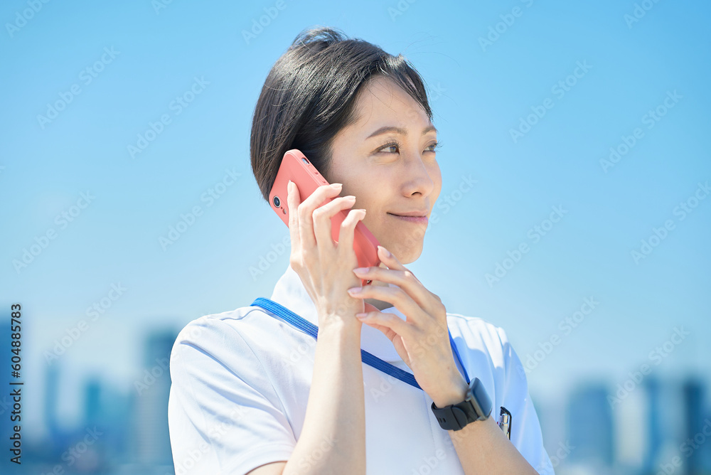 スマートフォンを手にする白衣の女性
